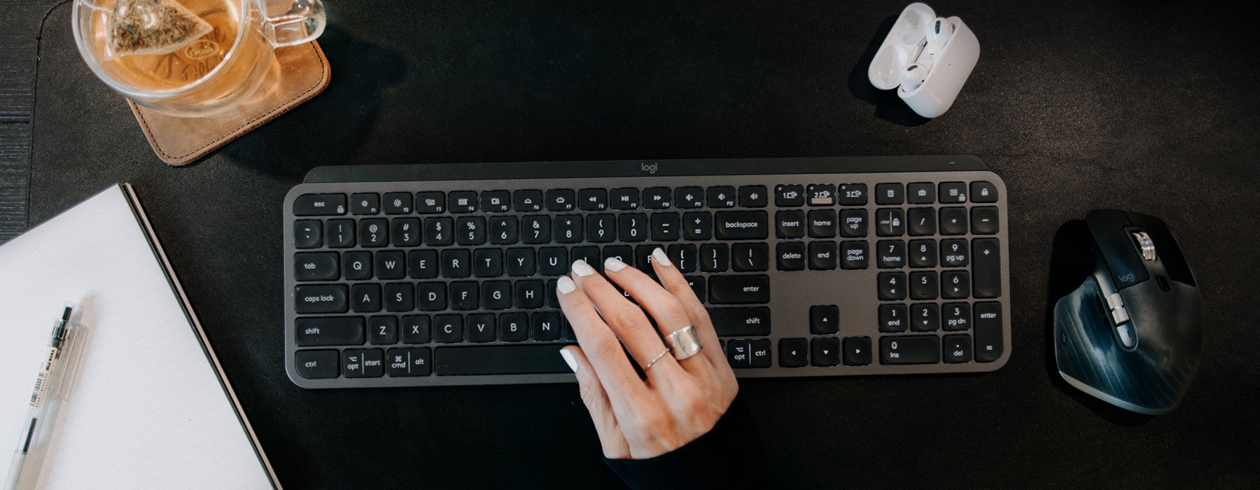 view from above of a woman's hands typing beside a coffee and office items
